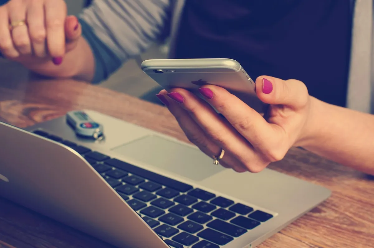 Accountant checking a phone beside a laptop, the leads UAE accounting firms lose without qualification