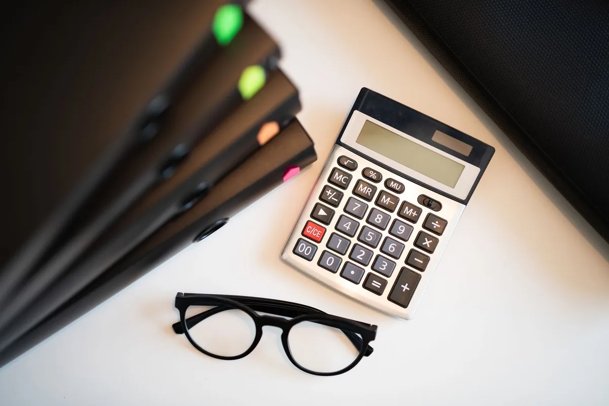 Calculator, glasses and folders on a desk, rolling out lead qualification without disrupting partners