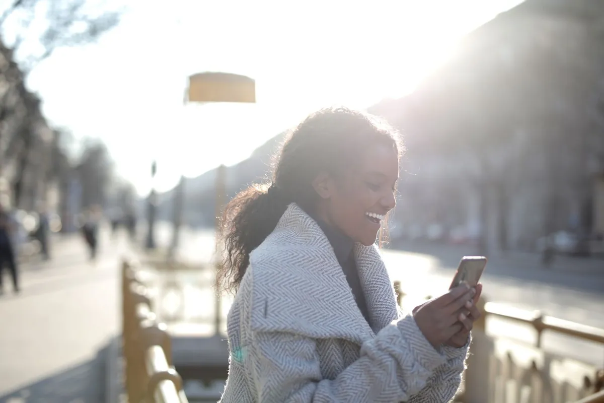 Woman smiling while texting outdoors, how the missed-call-to-conversation workflow works